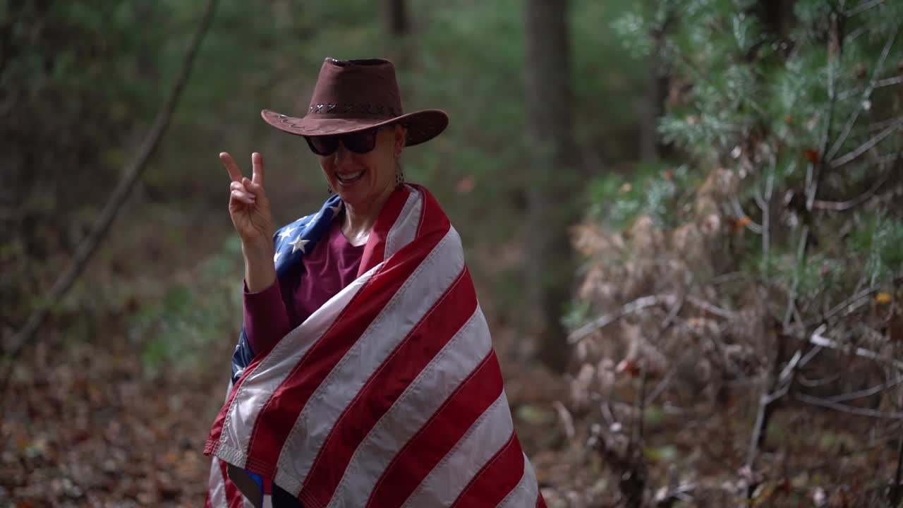 Woman draped in American flag in the forest