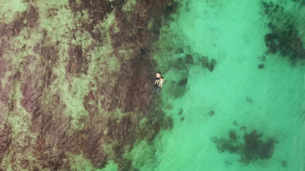 una pareja buceando en aguas turquesas.