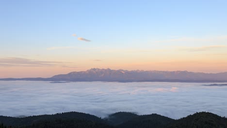 sunrise over a sea of clouds over podhale with tatra mountains visible in the distance.  taken from observation tower on luban.