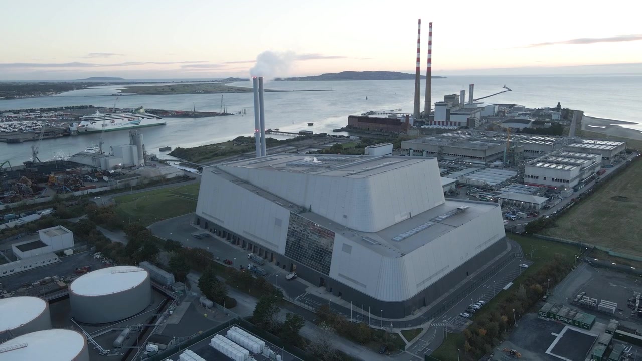 Waste-to-energy plant at Poolbeg and Port of Dublin with distant coastal view at sunset