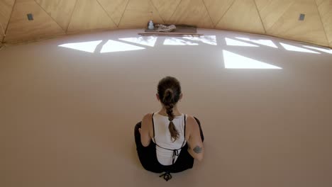 rearview of yoga poses rocking to stretch and breathing exercises in a calming outdoor studio with a hispanic woman