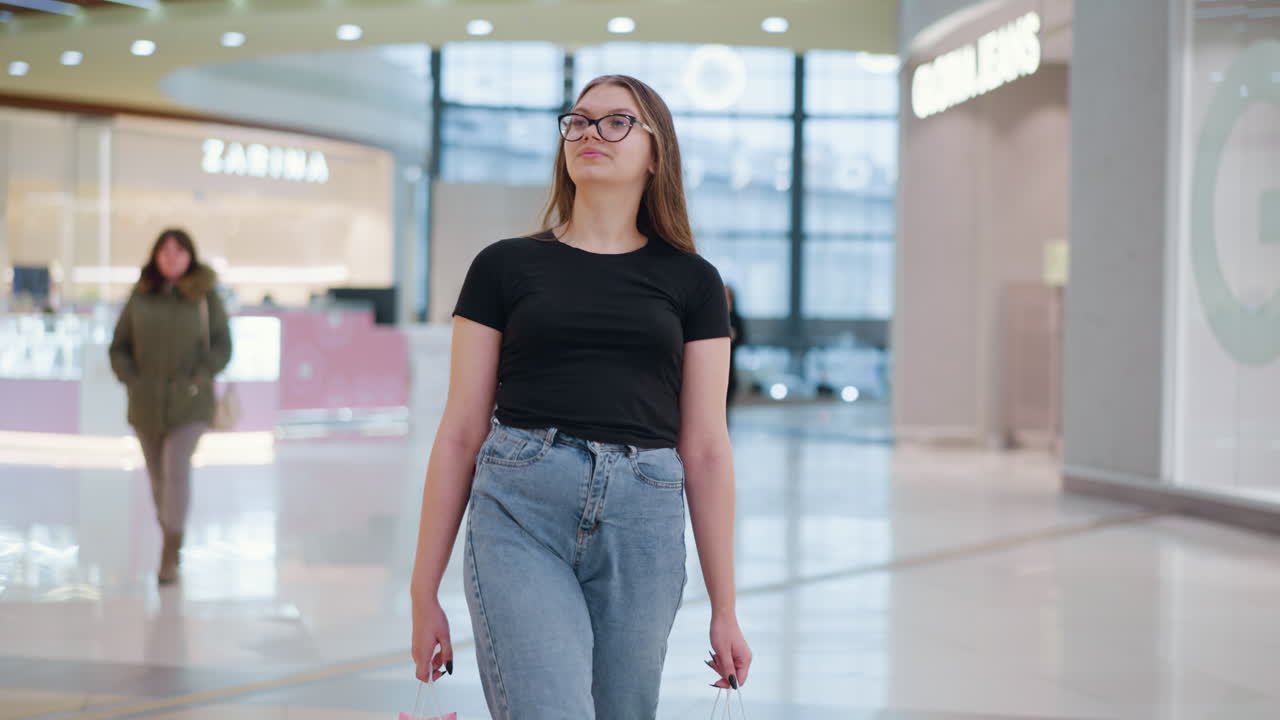 joven con bolsas de compras, girando y mirando a su alrededor con curiosidad en un centro comercial, con otros compradores pasando, mostrando una vibrante y ocupada atmósfera de compras