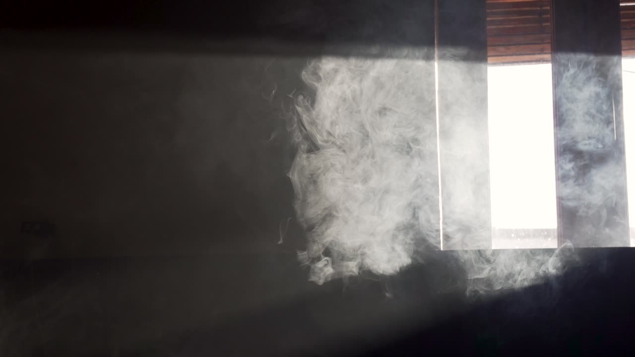 humo procedente del lado derecho de la toma en una habitación oscura con luz procedente de la ventana
