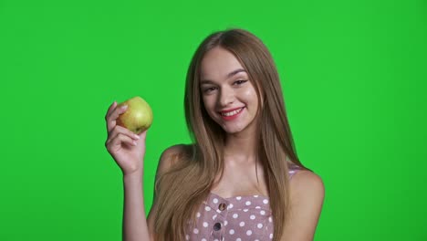 smiling girl wearing summer dress smiling and holding green apple