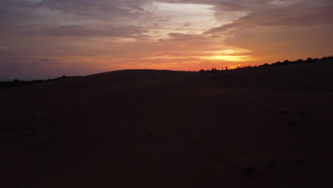 silueta de dunas de arena roja contra el atardecer amarillo brillante, vista aérea