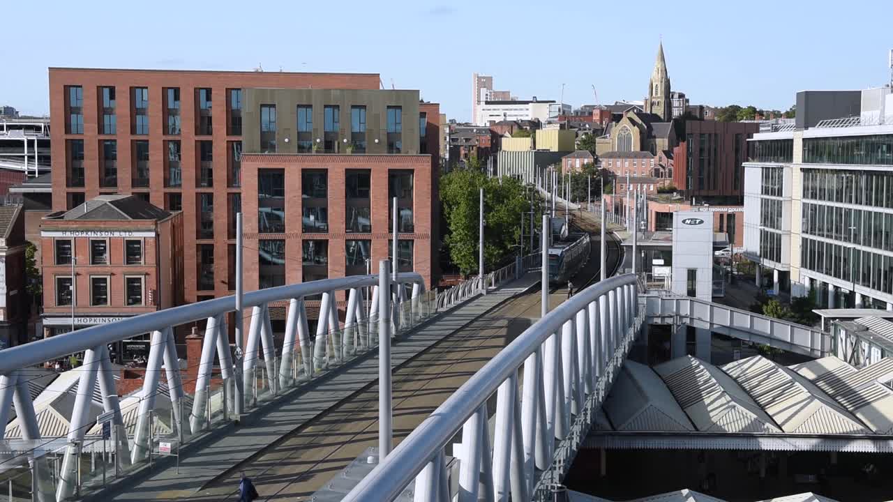 Overlooking the Nottingham tram passing by Nottingham Station with the city skyline in the background. This urban scene captures public transport and the cityscape of Nottingham, England