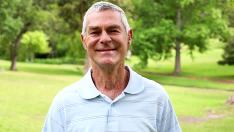 retired man in the park smiling at camera