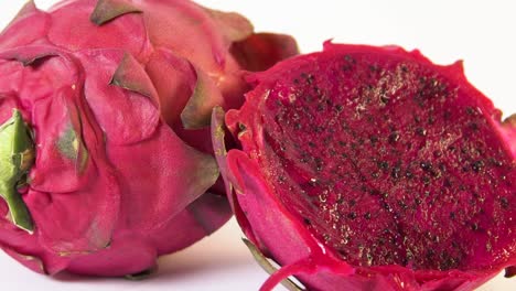 slow motion rotating shot of dragon fruit sliced in half and whole dragon fruit behind