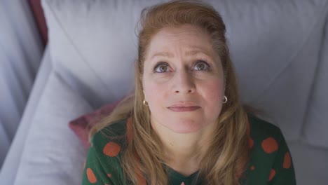 Thoughtful-old-woman-sitting-on-sofa-at-home.