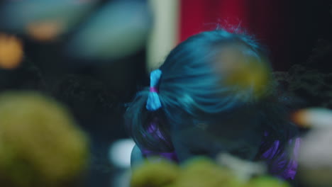 little girl looking at fish in aquarium curious child watching colorful sea life swimming in tank learning about marine animals in underwater ecosystem inquisitive kid at oceanarium