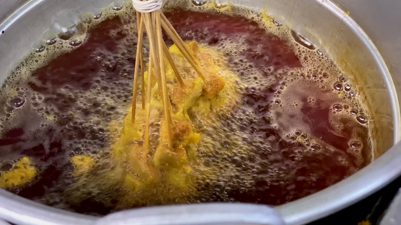 Cibo che frigge in padella con olio scuro.
