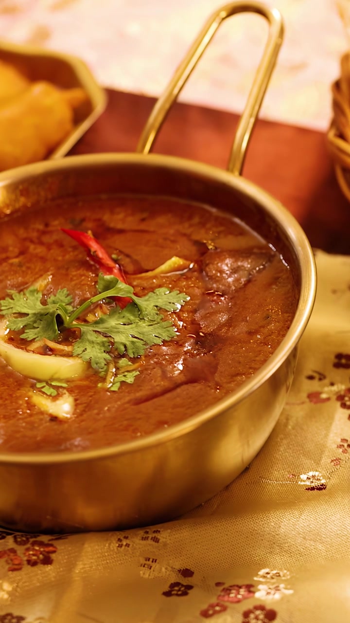 Panoramica ravvicinata di diversi piatti indiani, tra cui curry piccante, biryani e naan fresco.