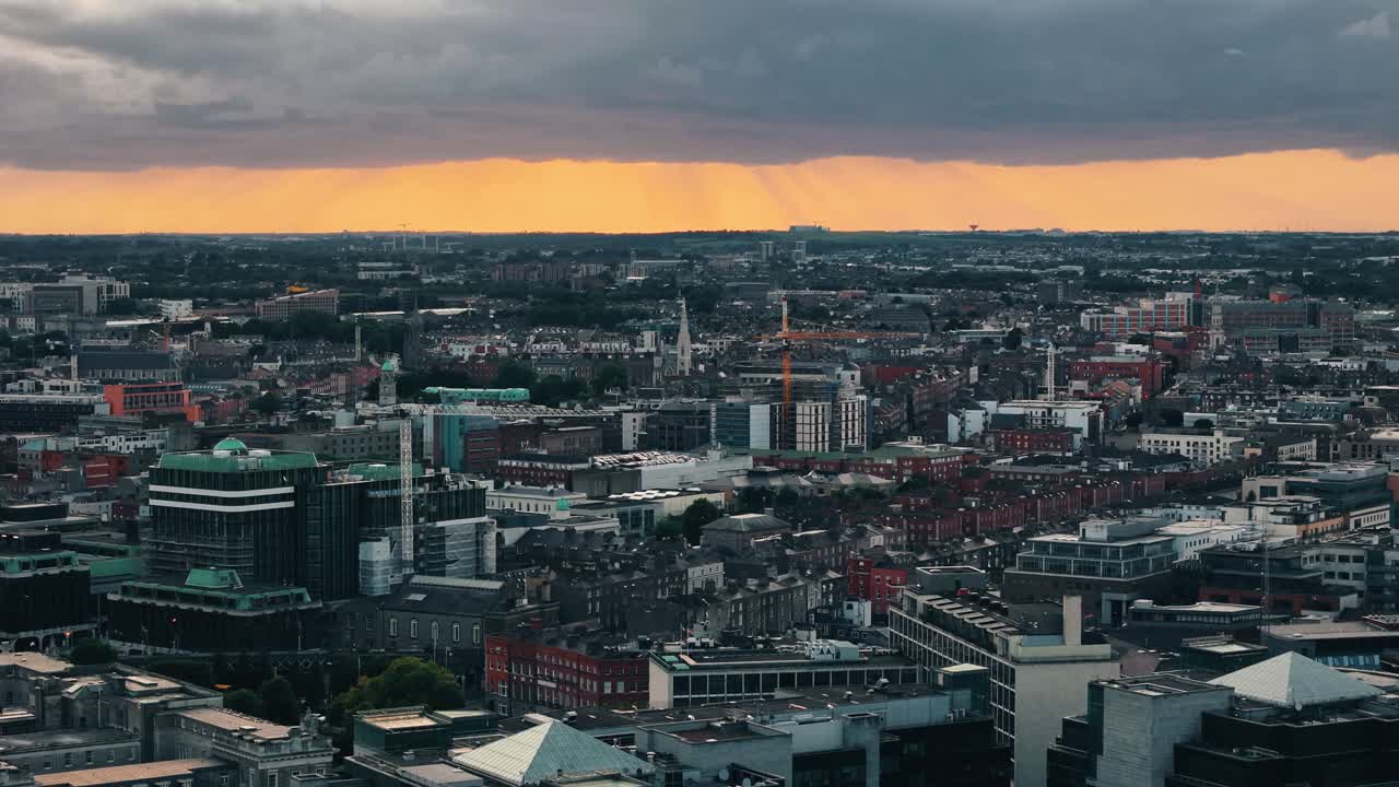 Slow dolly left over Dublin skyline at sunset with glowing orange sky and rooftops in