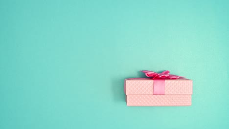 pastel pink gift appear and open on cyan background. stop motion