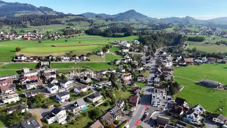 Aerial-panning-shot-of-swiss-city-named-Eschenbach-surrounded-by-green-fields-and-mountains-in-summer