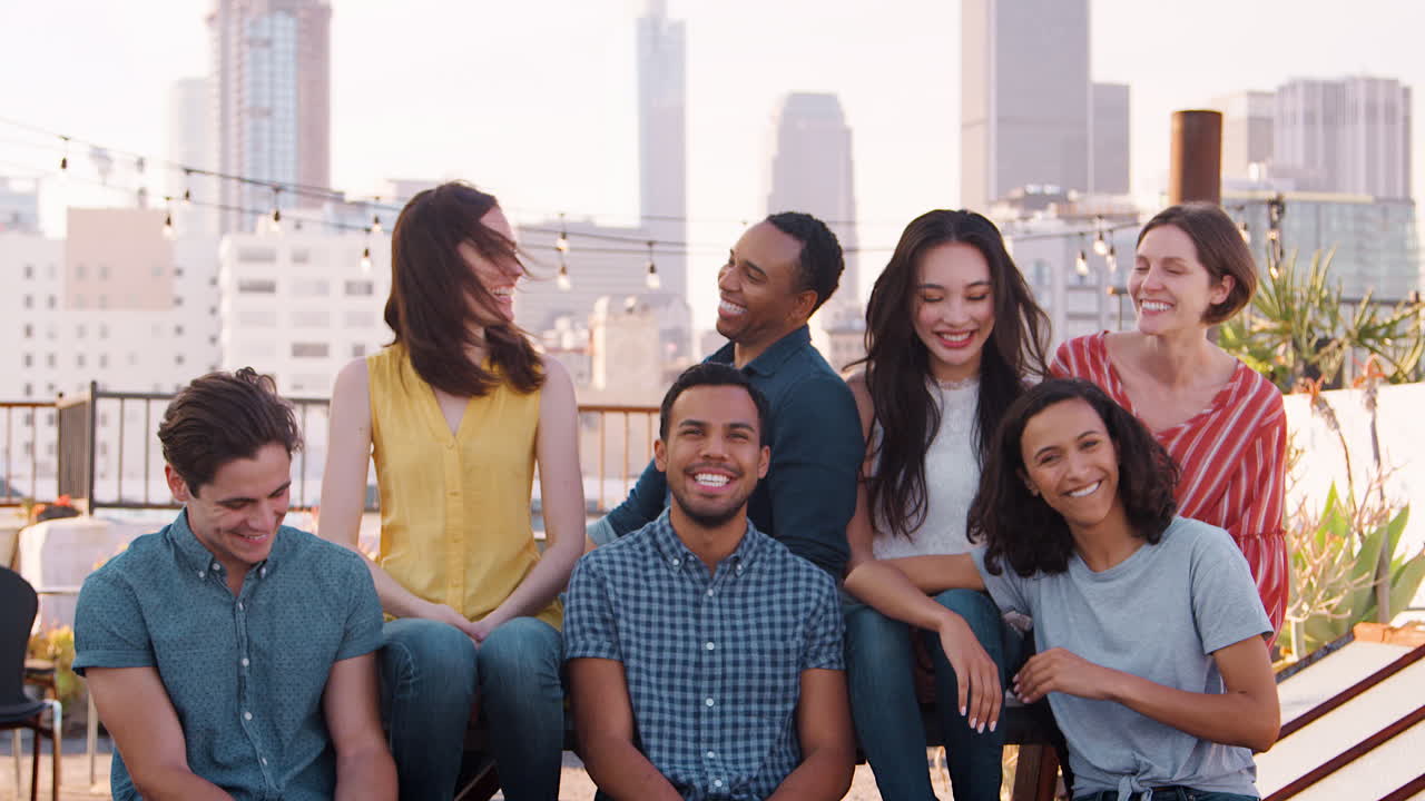 retrato de amigos reunidos en la terraza de la azotea para una fiesta con el horizonte de la ciudad en el fondo
