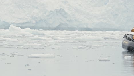 Zodiac-enters-frame-in-Antarctica-in-front-of-a-big-stunning-glacier-during-snow