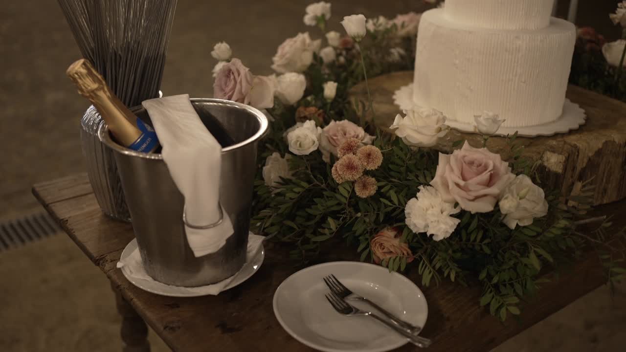 Wedding cake table with floral decorations, champagne bucket, and tableware