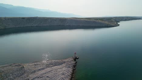 Early-morning-sun-over-coastal-Adriatic,-island-Pag-light-beacon-and-bridge-in-Croatia-from-above