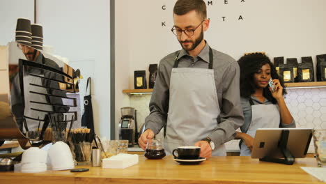 Kaukasischer-Männlicher-Barista-Und-Kaukasische-Mitarbeiterin,-Die-In-Einem-Modernen-Café-Arbeiten