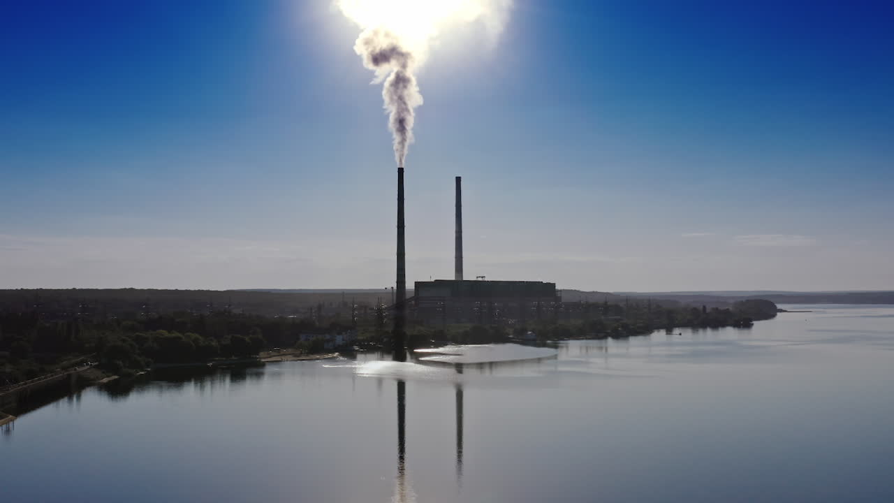 Smokestack in factory with blue cloudless sky. Sunset above modern factory. Panoramic video with drone.