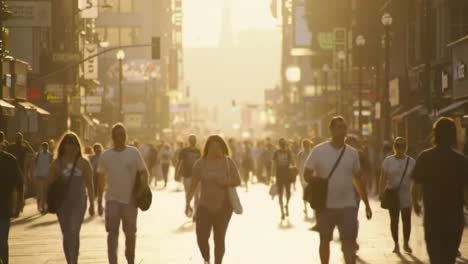 a bustling urban street scene at sunset, capturing the vibrant energy of pedestrians commuting in the golden hour light and the lively city atmosphere.