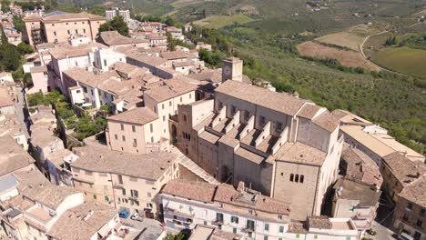 wide angle drone shot panning downwards towards a very old church on top of a hill surrounded by old homes