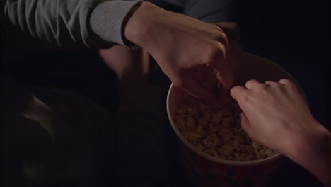 Female-and-male-hand-take-popcorn-grains-from-popcorn-box-in-slow-motion