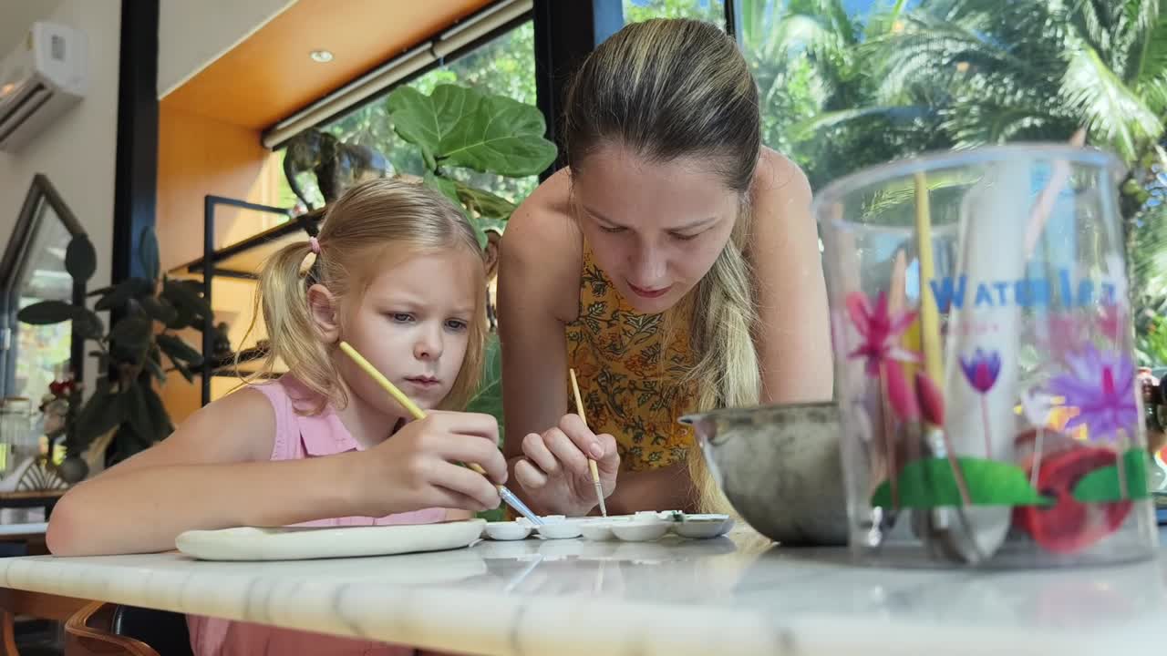 madre e hija pintando cerámica en un café