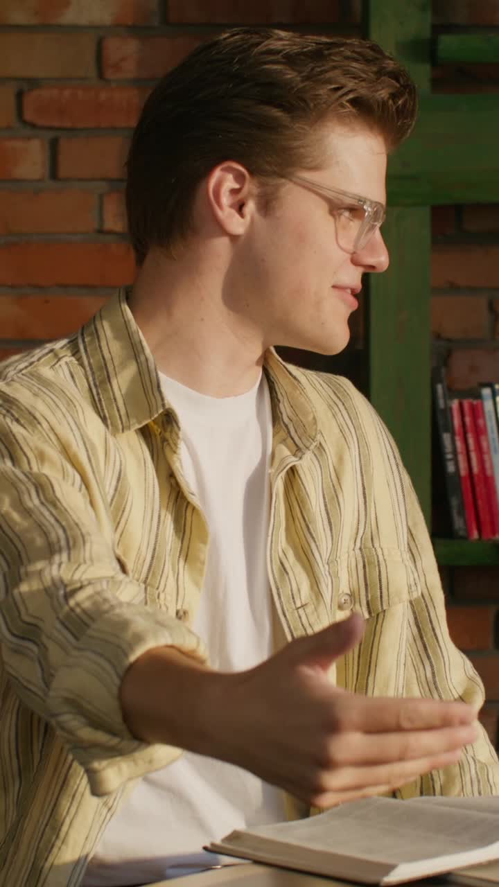 un joven hablando y leyendo en un café.