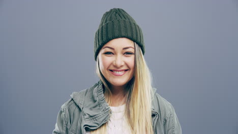 a cheerful young woman posing against a grey