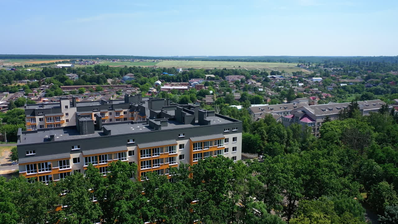 New apartment building on urban background. Block of flats among green trees. Modern high-rise building in the city. Aerial view.