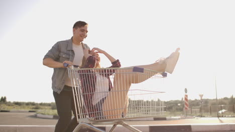 un hombre corre y empuja un carrito de supermercado rodando una chica en él loca diversión de los estudiantes