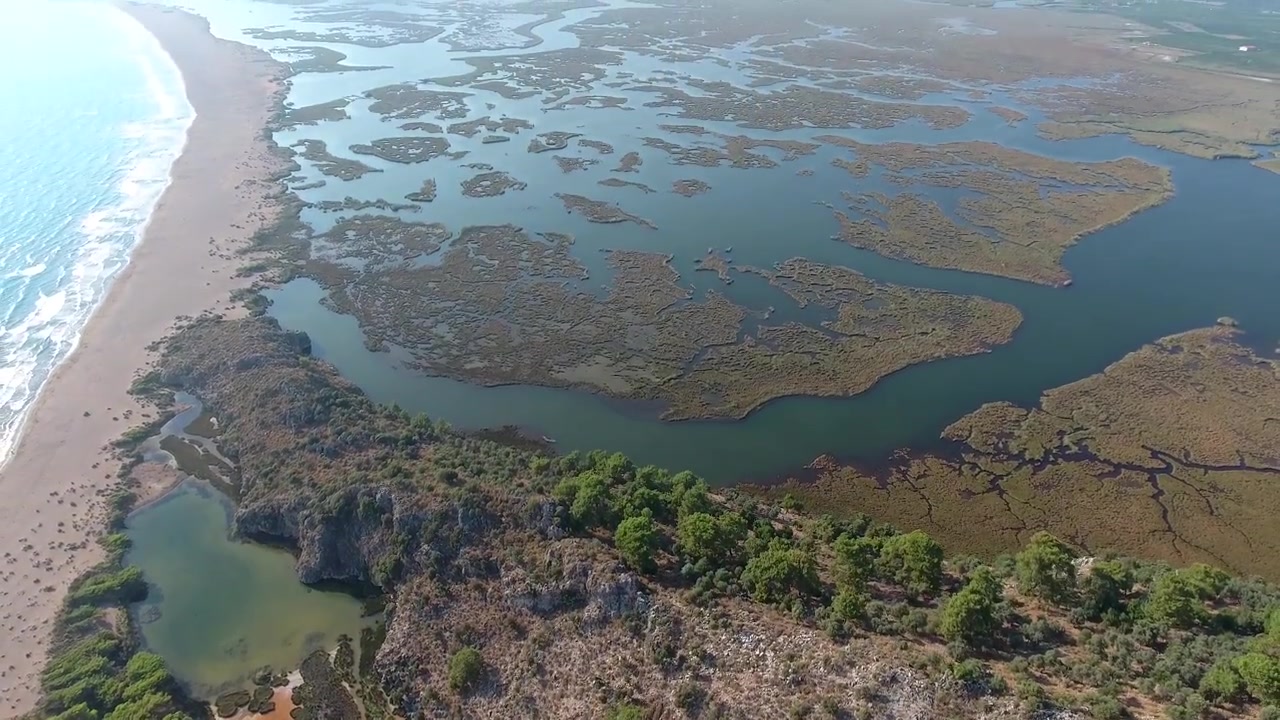 Vista aerea di zone umide costiere e spiaggia sabbiosa.