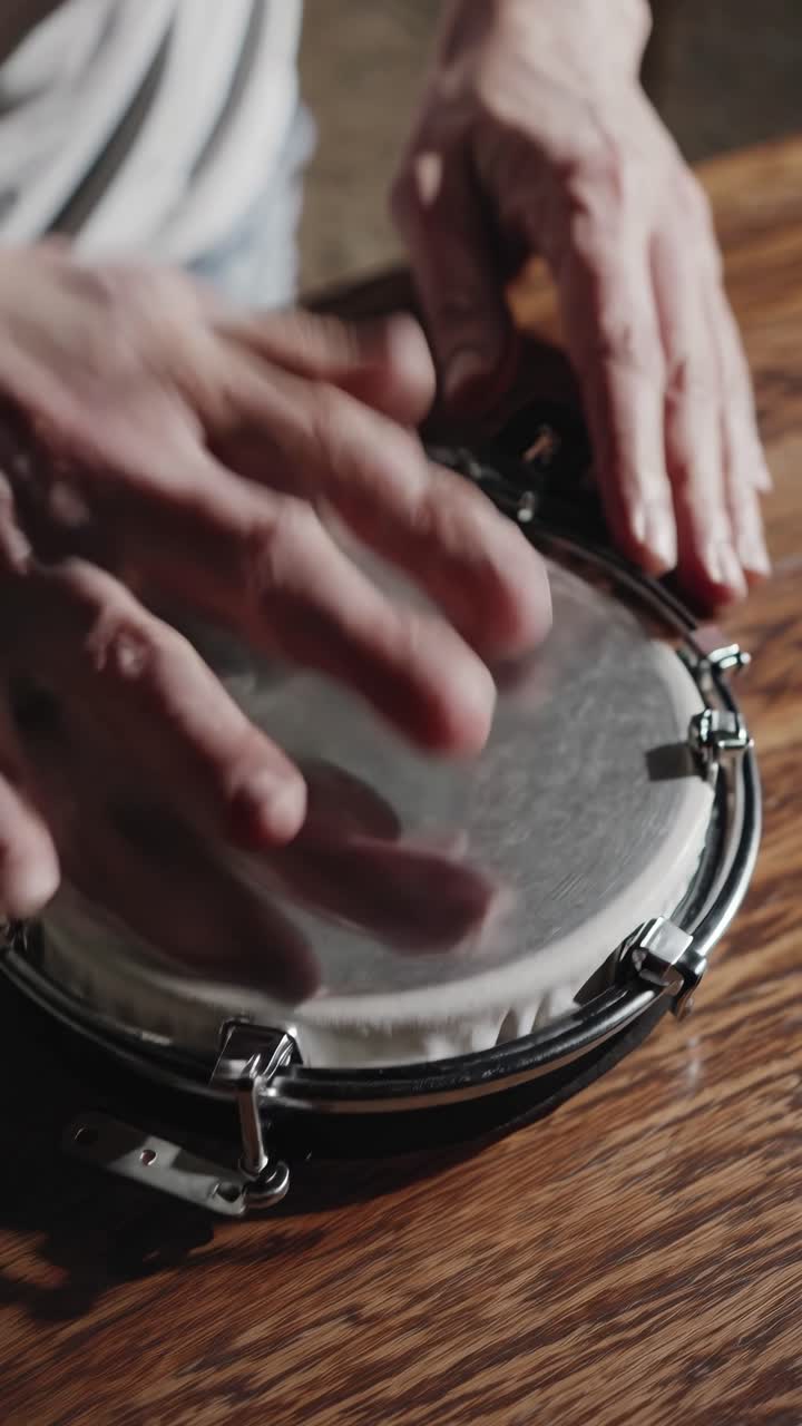 Primo piano di mani che suonano un piccolo tamburo a percussione su un tavolo di legno