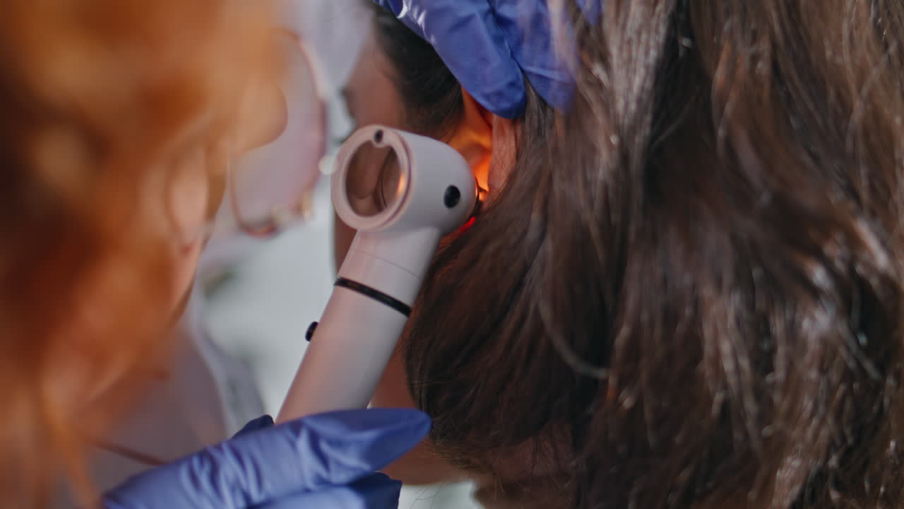 Professional medic using otoscope at ear examination in health clinic closeup