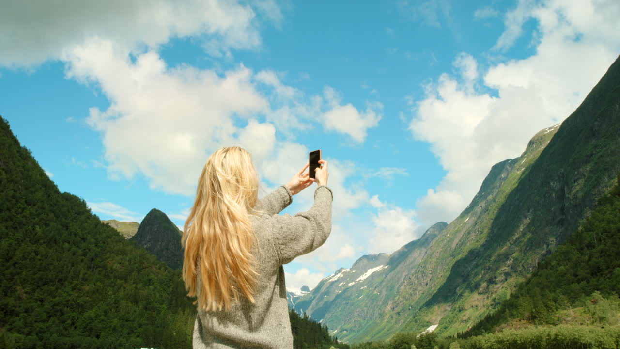 mujer tomando una foto de un paisaje de fiordo noruego