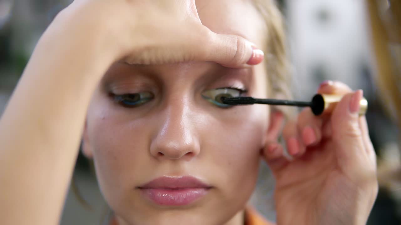 Make-up artist applying eyelash makeup to model's eye. Mascara .Close up view