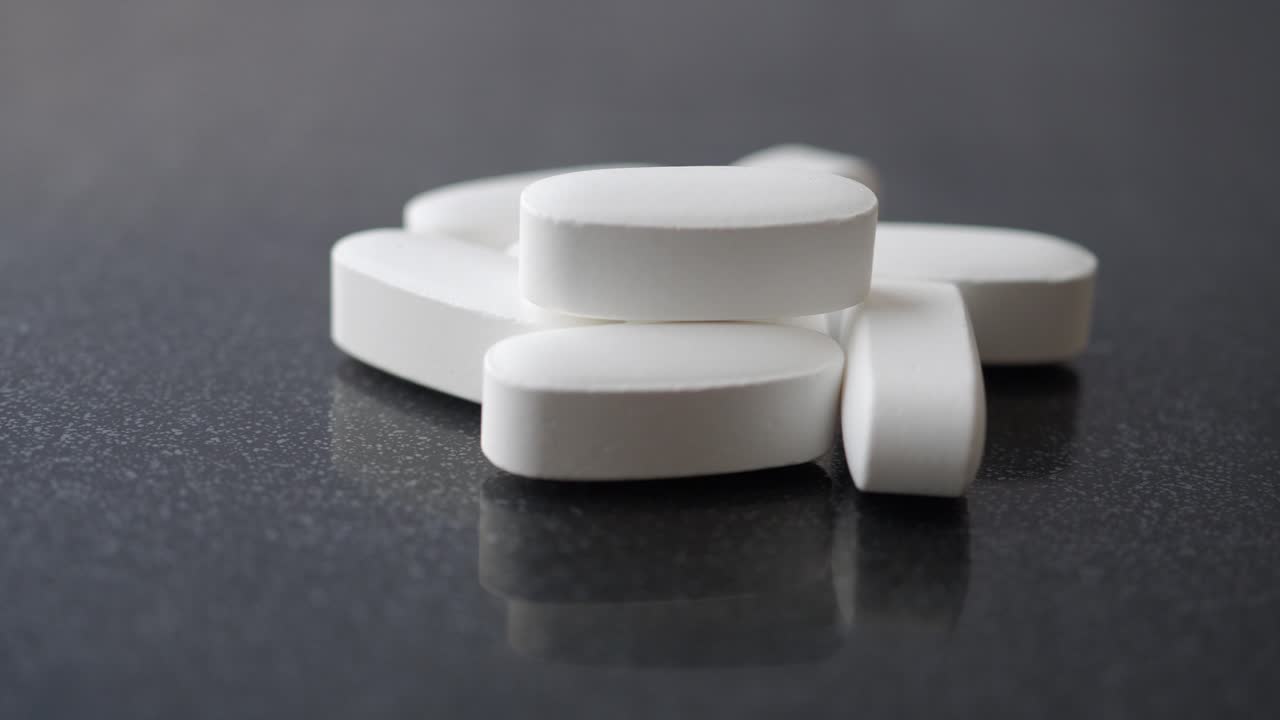 pastillas ovaladas blancas en superficie oscura