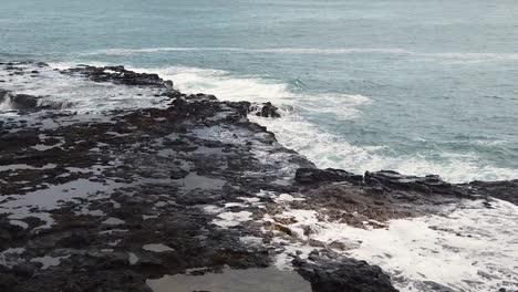 hd slow motion hawaii kauai right to left pan landing with spouting horn blowhole in right of frame and water swirling up through hole in lava rock in left of frame