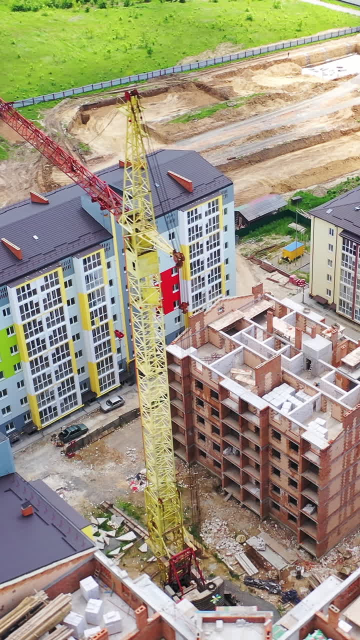 Construction site of a modern district in the city. Colorful urban buildings in a new microdistrict. Building with a bird's eyes. Vertical video