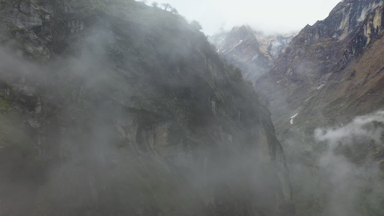 네팔 안나푸르나 산맥의 계곡 안에 안개가 자욱한 절벽의 서사시 공중 회전 샷