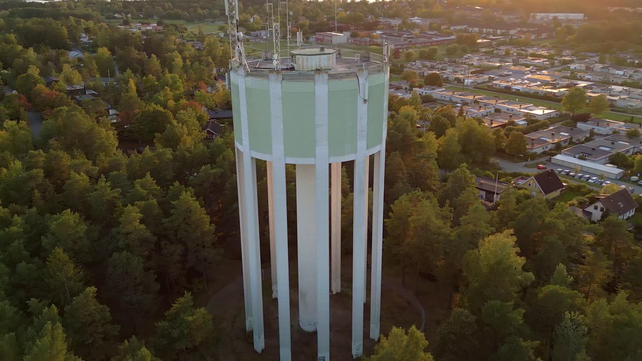 vista aérea de una torre de agua y área residencial en la puesta de sol con luz de fondo