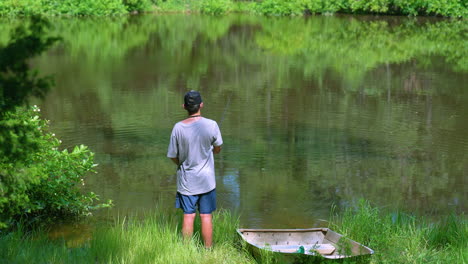 Teen-casting-a-fishing-rod-on-the-shore-of-a-scenic-rural-pond