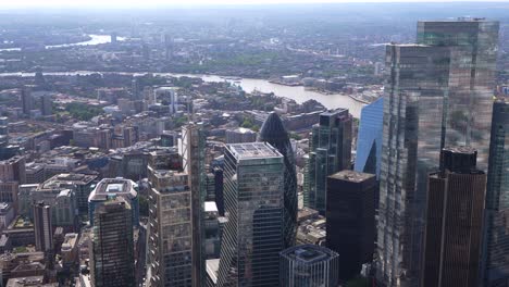 Vista-Aérea-De-Cerca-De-Las-Torres-De-La-Ciudad-De-Londres,-Incluido-Leadenhall-Y-El-Pepinillo-Con-Canary-Wharf-Al-Fondo.