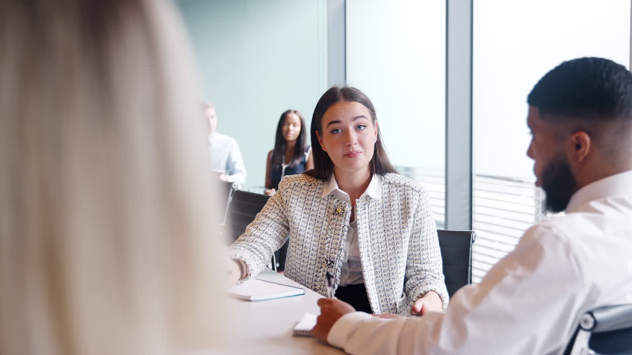 Group Collaborating On Task At Graduate Recruitment Assessment Day Whilst Being Observed By Recruitment Team