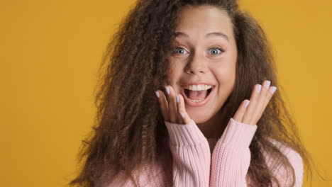 excited caucasian curly haired woman smiling to the camera.