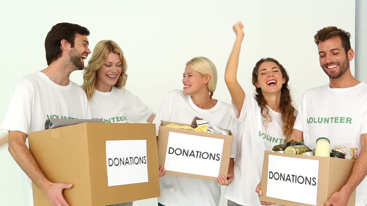equipo de voluntarios sosteniendo cajas de donaciones y animando