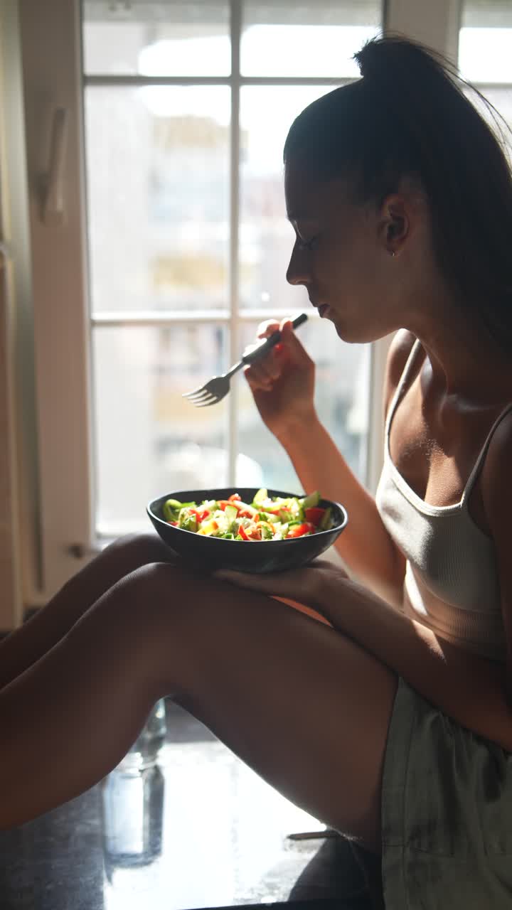 mujer comiendo ensalada en la cocina