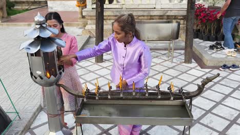 women praying and lighting candles at a thai temple
